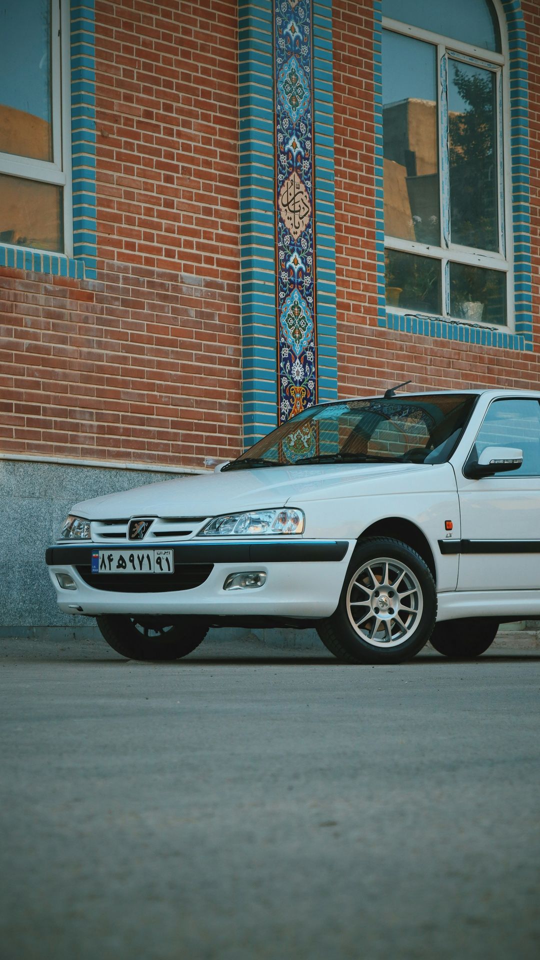 white bmw x 6 parked beside brown brick building during daytime